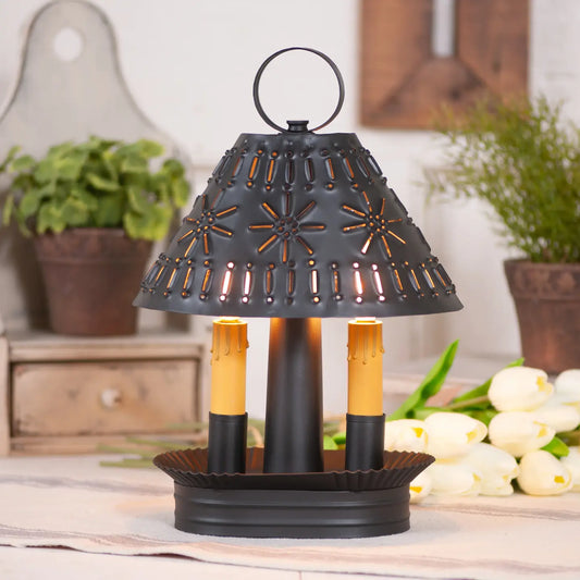 Decorative black lantern with candles on a table, surrounded by plants and flowers.
