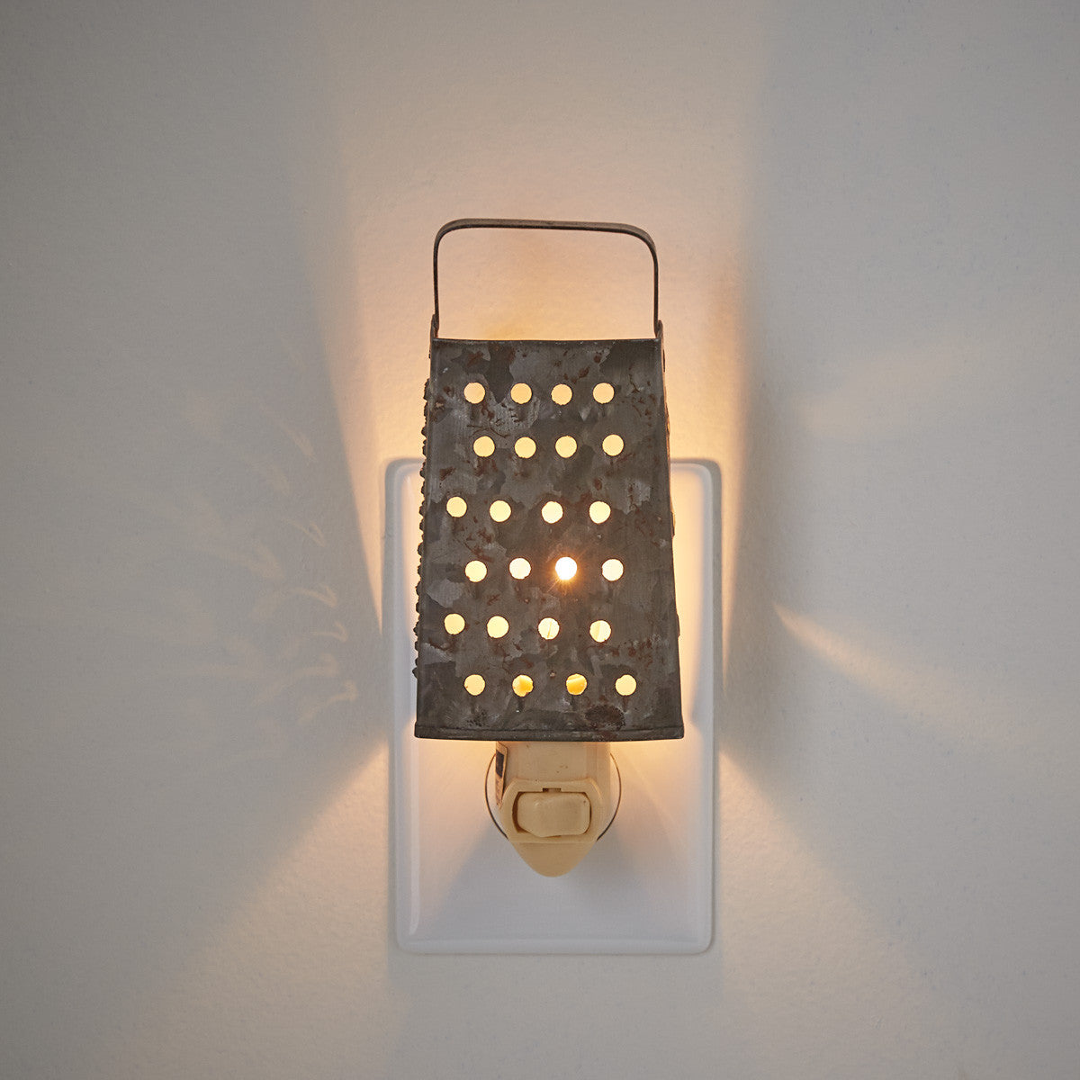 A grater night light with a metal grating and a light source mounted on a wall.