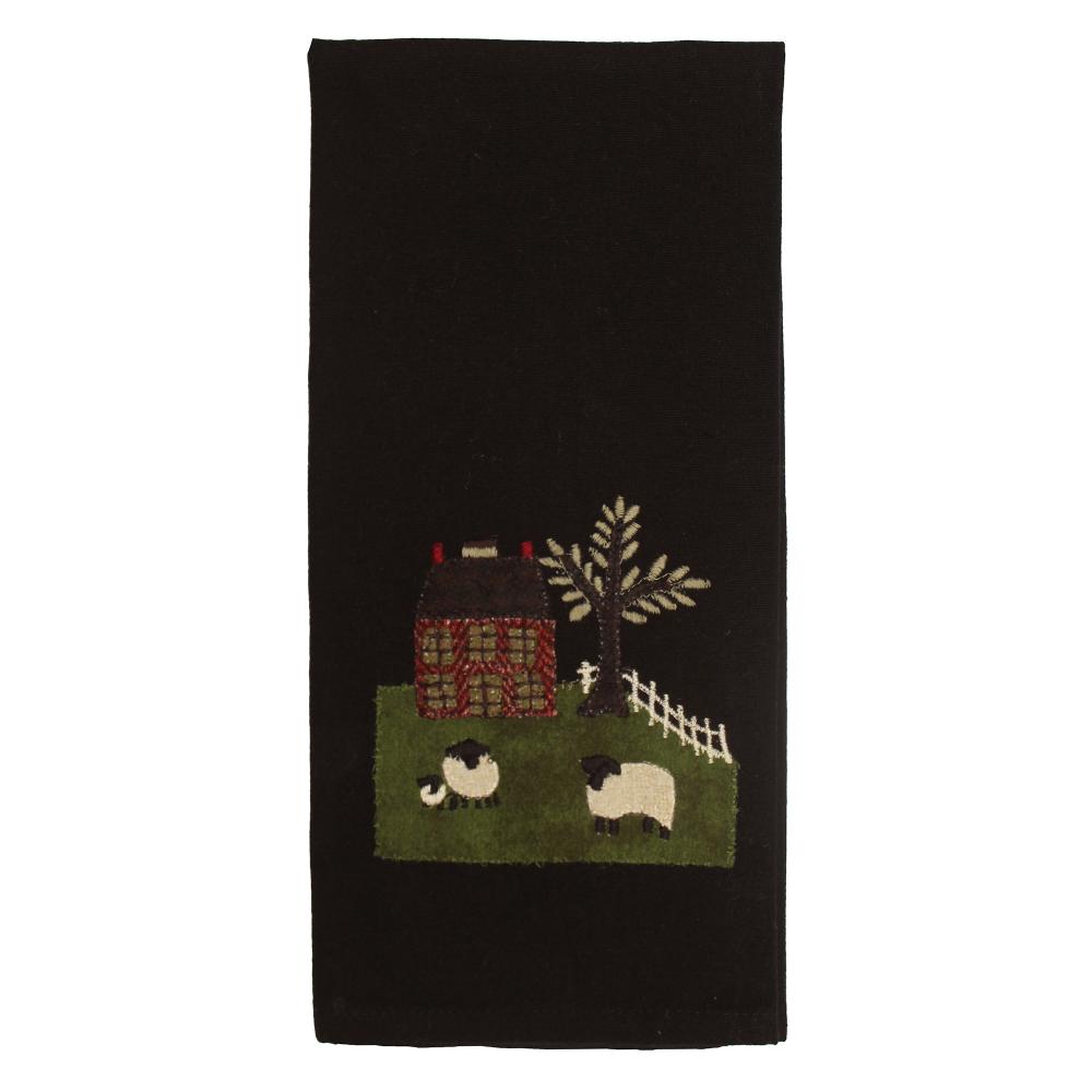 Black towel with a embroidered design of a cabin, trees, and sheep on a white background