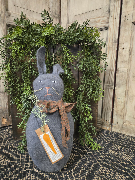 Decorative bunny with carrot and greenery on a wooden surface
