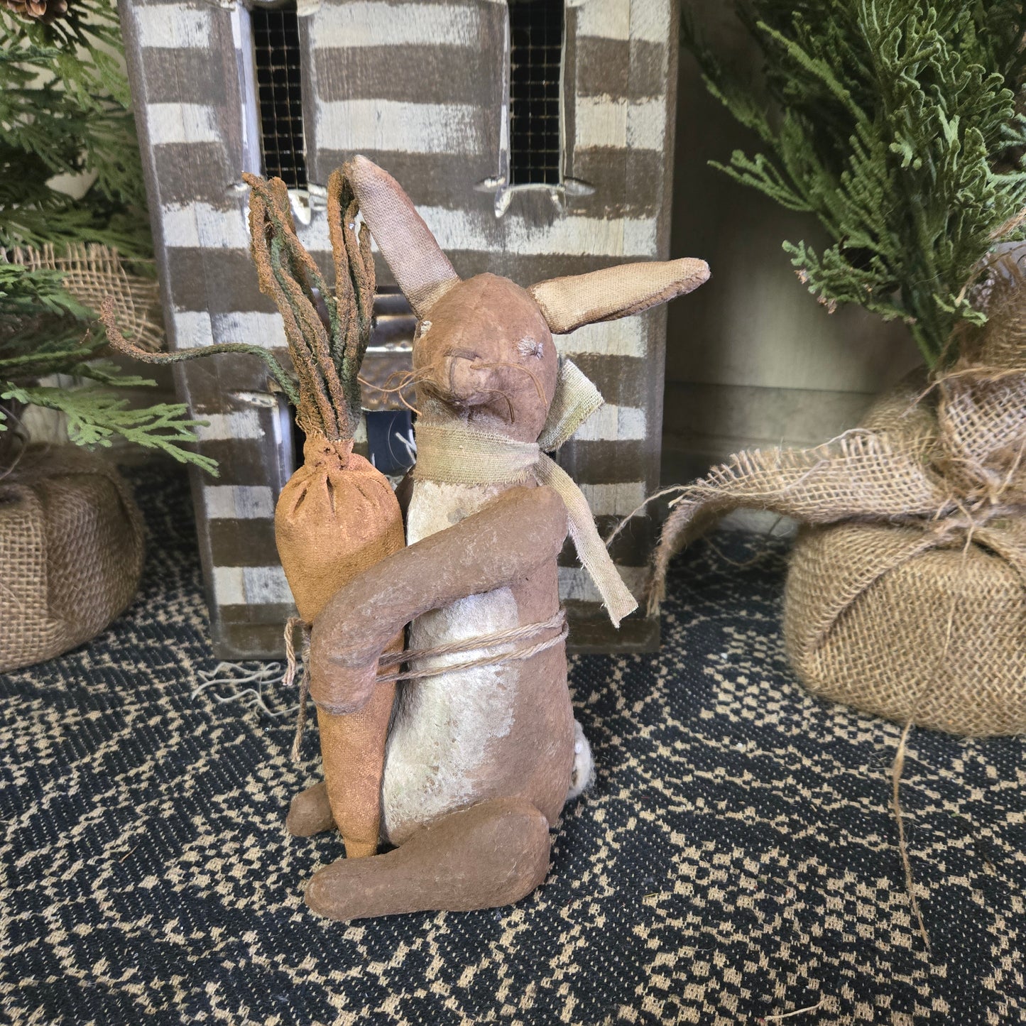 A beige bunny figurine with a carrot, Primitive style, displayed in an interior setting.
