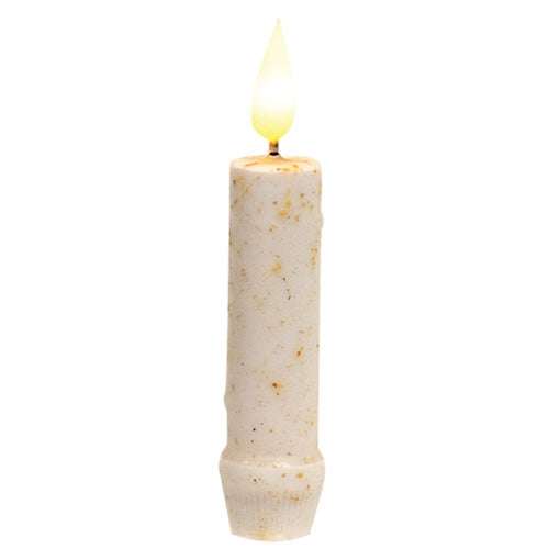 A single cream-colored pillar candle with small brown speckles and a glowing flame, isolated on a white background.