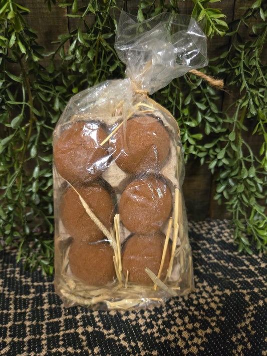 Packaged brown eggs on a textured surface with greenery