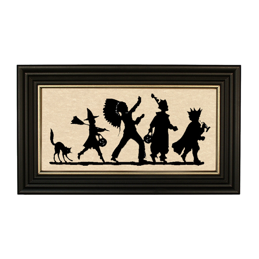 A framed paper cut silhouette artwork featuring a parade with characters in costumes and a black background, placed on a white wall.