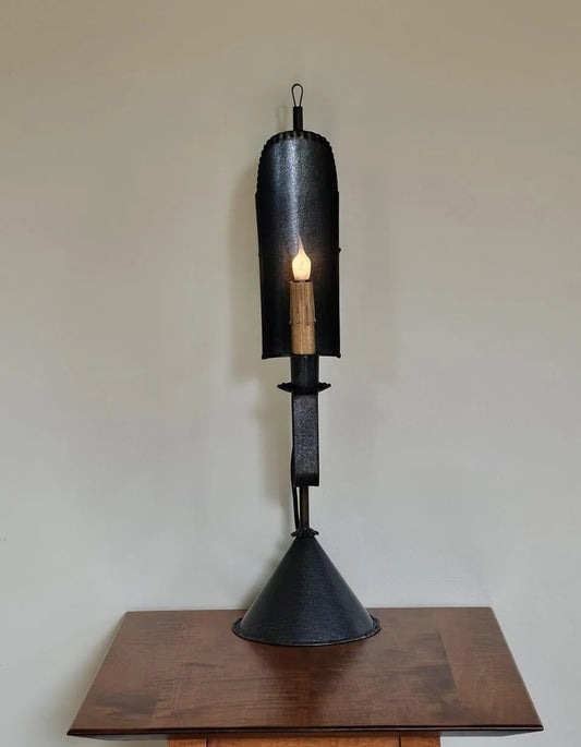 Simple tin table lamp with triangular base and a sconce mounted on top with a candle light source