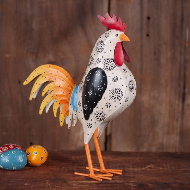 Decorative rooster figurine with colorful eggs on a wooden surface