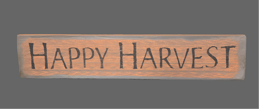 Pumpkin colored wood sign with the words "Happy Harvest" in black