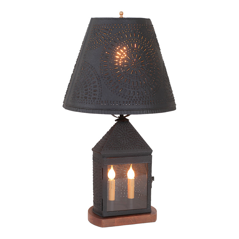 Decorative table lamp with black shade and glass base on a white background