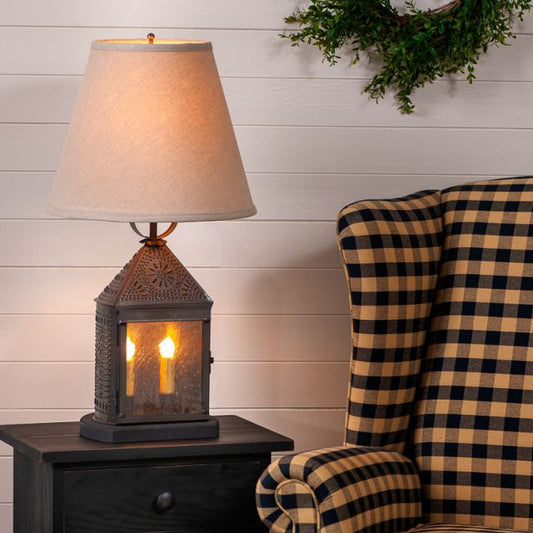 Decorative table lamp on a side table next to a plaid chair against a white paneled wall.