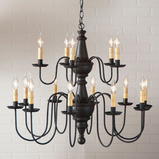 Black chandelier with multiple candle-style lights against a light brick wall.