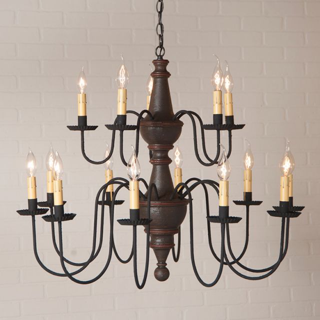Vintage-style chandelier with multiple candle-like lights against a light brick wall.