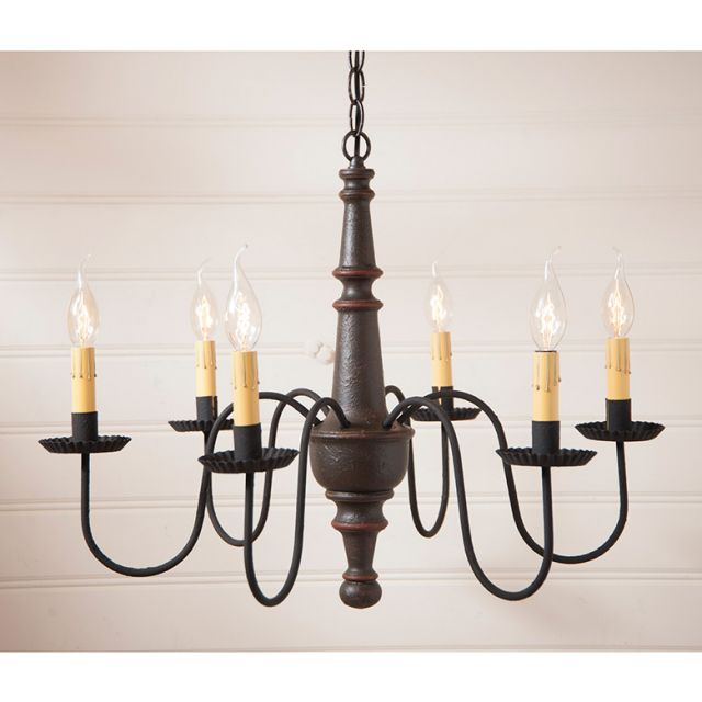 Six arm primitive wooden chandelier hanging in front of cream brick wall