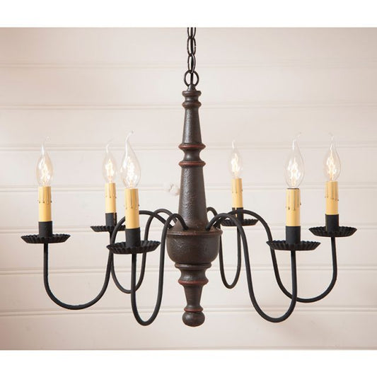 Six arm primitive wooden chandelier hanging in front of cream brick wall