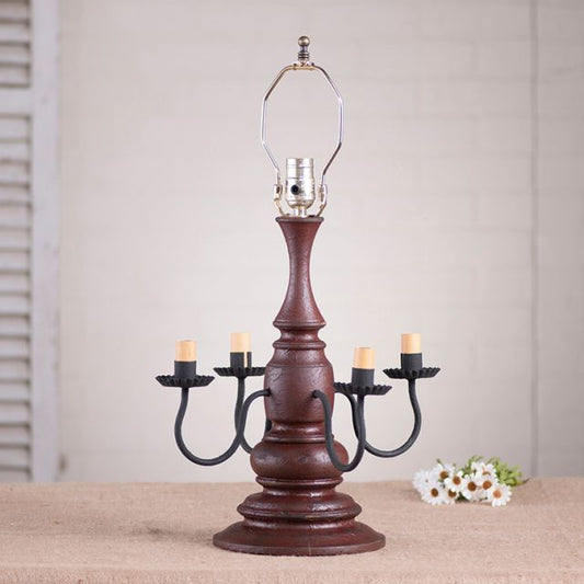 Red wooden lamp with four candelabra sockets against a white background with daisies next to it