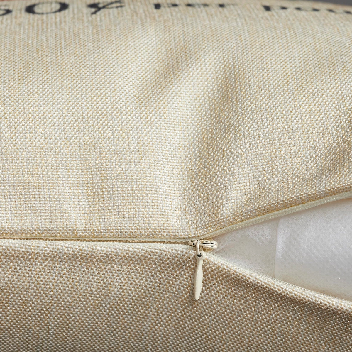 Close-up of the pillow cover’s open zipper, showing cream woven fabric and the white pillow insert inside.