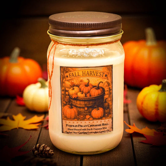 Jar candle labeled 'Fall Harvest' with pumpkins and leaves on a wooden surface