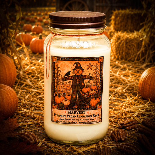A jar candle labeled 'Harvest Pumpkin Pecan Cinnamon Roll' by Mason, styled in a rustic autumn setting with hay, pumpkins, and pecans. The candle is in a clear glass jar with white wax, a dark brown lid, and a detailed fall harvest label.
