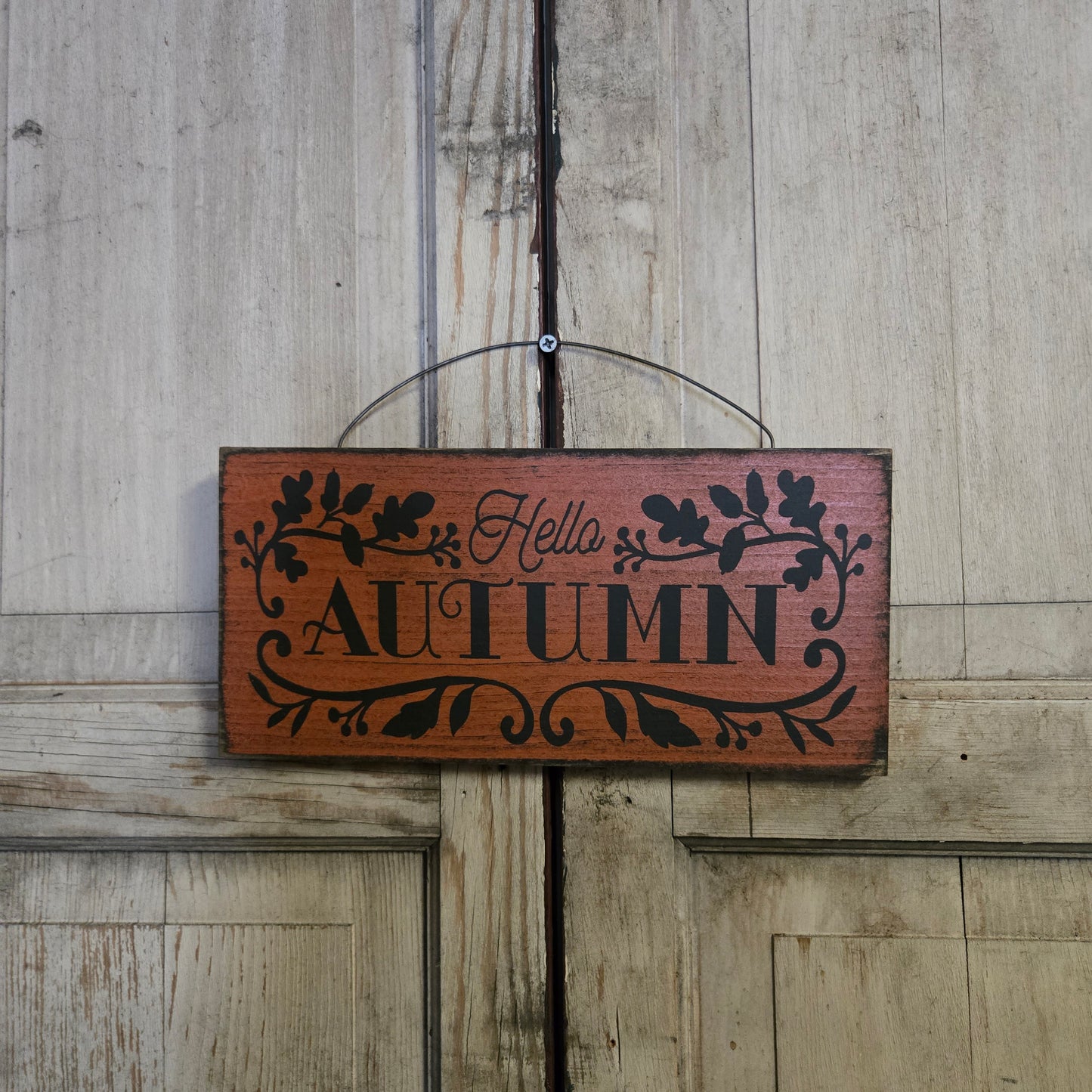Wooden sign with 'Autumn Hello' text on a wooden background