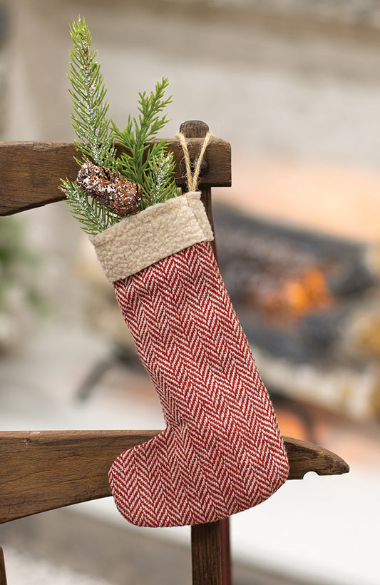 Herringbone stocking ornament with greenery inside hanging from a chair