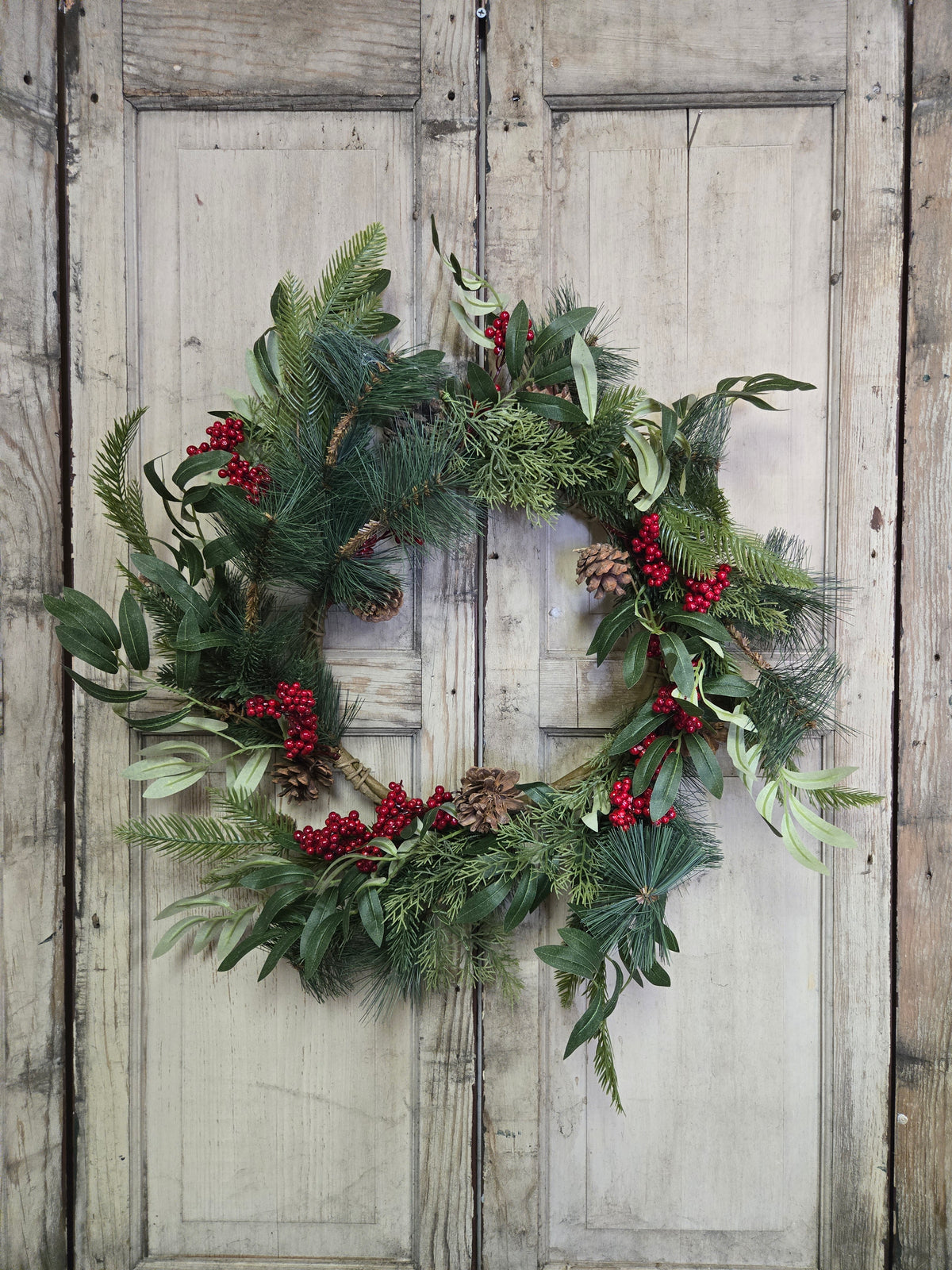 Christmas wreath with greenery and red berries on a wooden door
