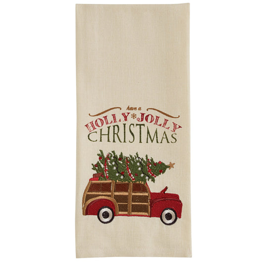 A beige embroidered dishtowel with 'Holly Jolly Christmas' text and a decorative holiday-themed design featuring a red and white vintage car.