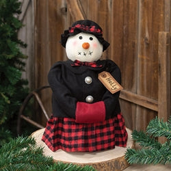 Decorative snowman figurine with a black coat, red plaid skirt, and checkered hat on a wooden base.