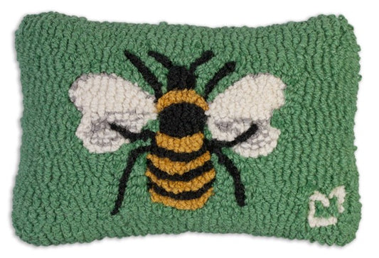 A rectangular hooked wool pillow with a green background featuring a detailed image of a honey bee on the front.