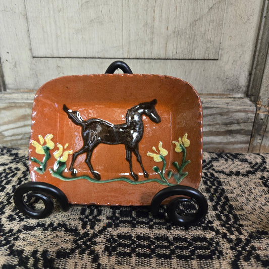 Small rectangular redware plate with horse and flower motive in a wrought iron plate stand