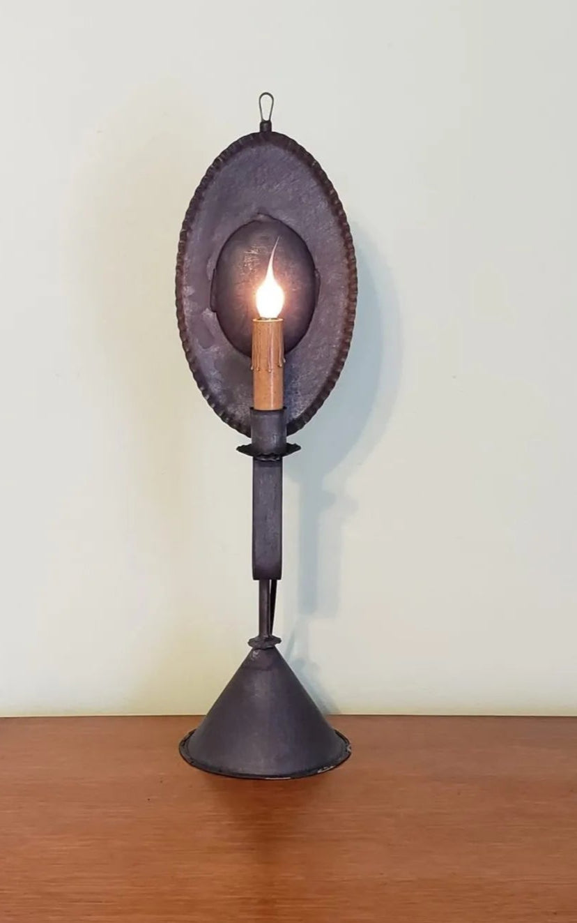 Decorative lamp with a metal shade on a wooden surface against a white wall