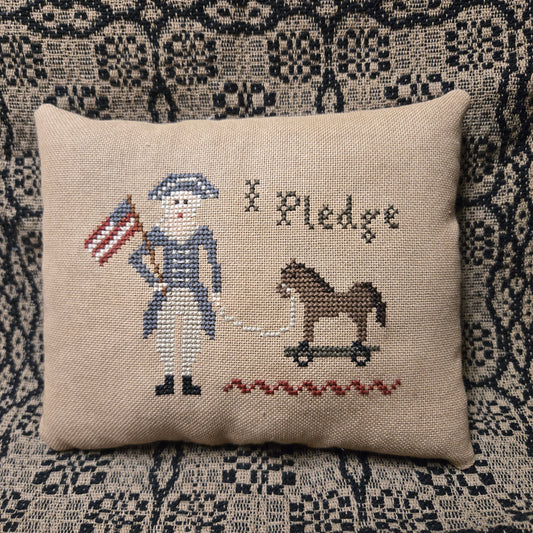 Decorative pillow with cross-stitched design of a soldier and flag on a textured surface