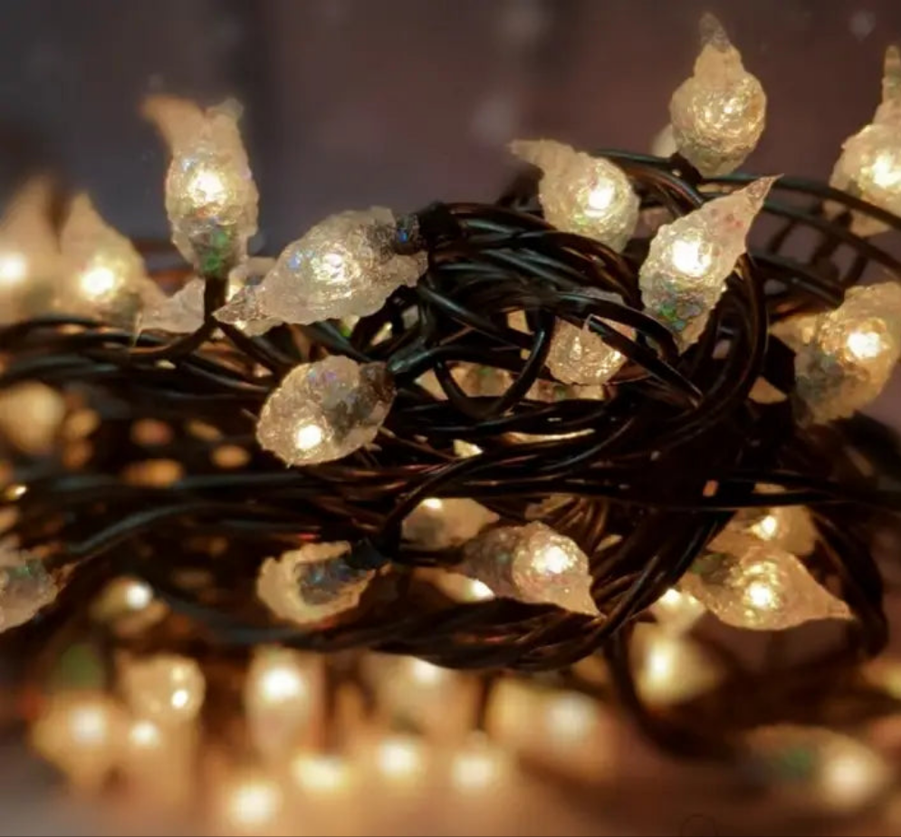 A close-up of a silicone string light with small clear lights attached to a black cord, resembling rice-shaped bulbs.
