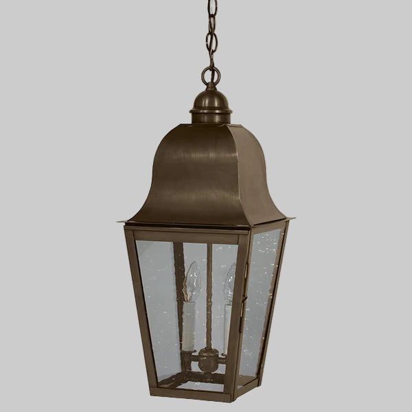 Bronze outdoor hanging lantern with glass panels on a gray background