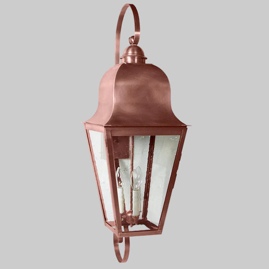 Copper outdoor wall lantern with clear glass on a gray background