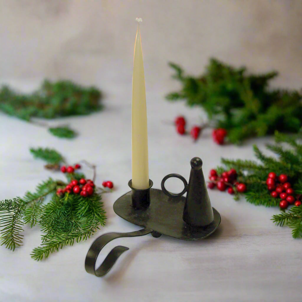 Decorative candle holder with a lit candle surrounded by greenery and berries on a light background