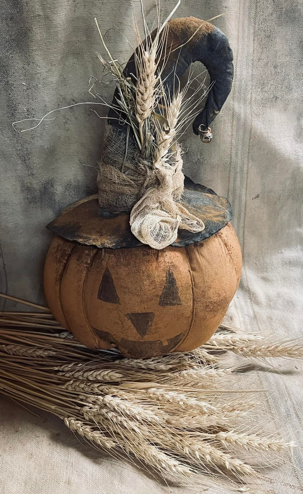 Decorative pumpkin with a hat and wheat on a textured background
