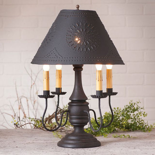 Decorative table lamp with black shade and candle-like lights on a white brick wall background.