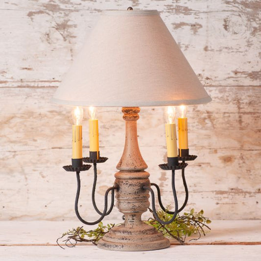 Decorative table lamp with a rustic base and beige lampshade against a wooden background