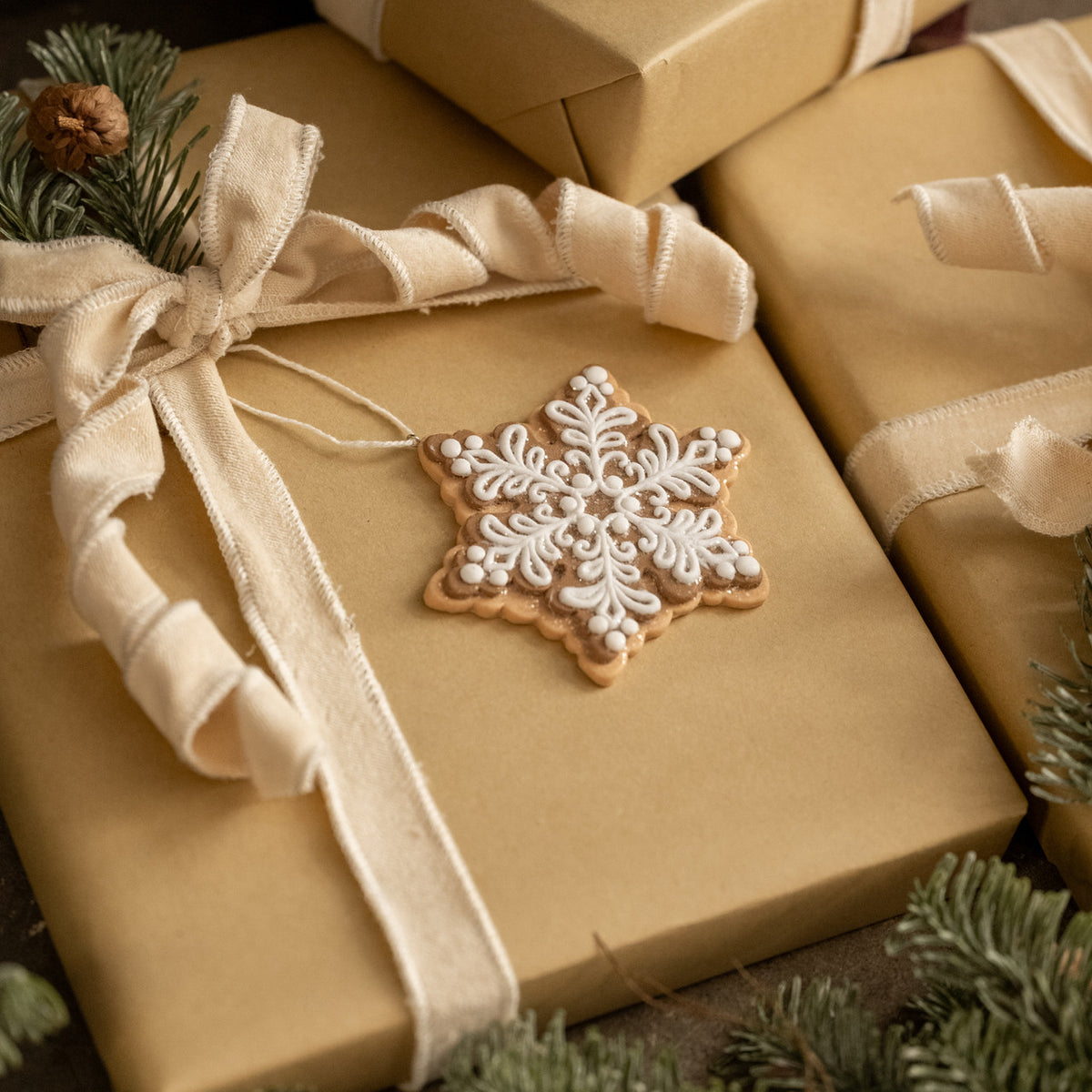 Gift box with a decorative snowflake cookie on top, surrounded by Christmas decorations.