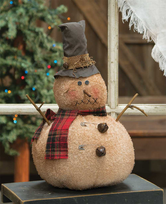Jingle bell snowman doll with top hat and plaid scarf with stick arms on bench with tree in background