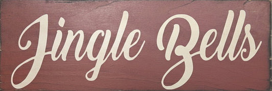 Wooden sign with 'Jingle Bells' text on a background of greenery