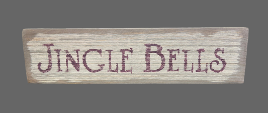 A wooden sign with 'JINGLE BELLS' written in bold letters, indicating a rustic style.