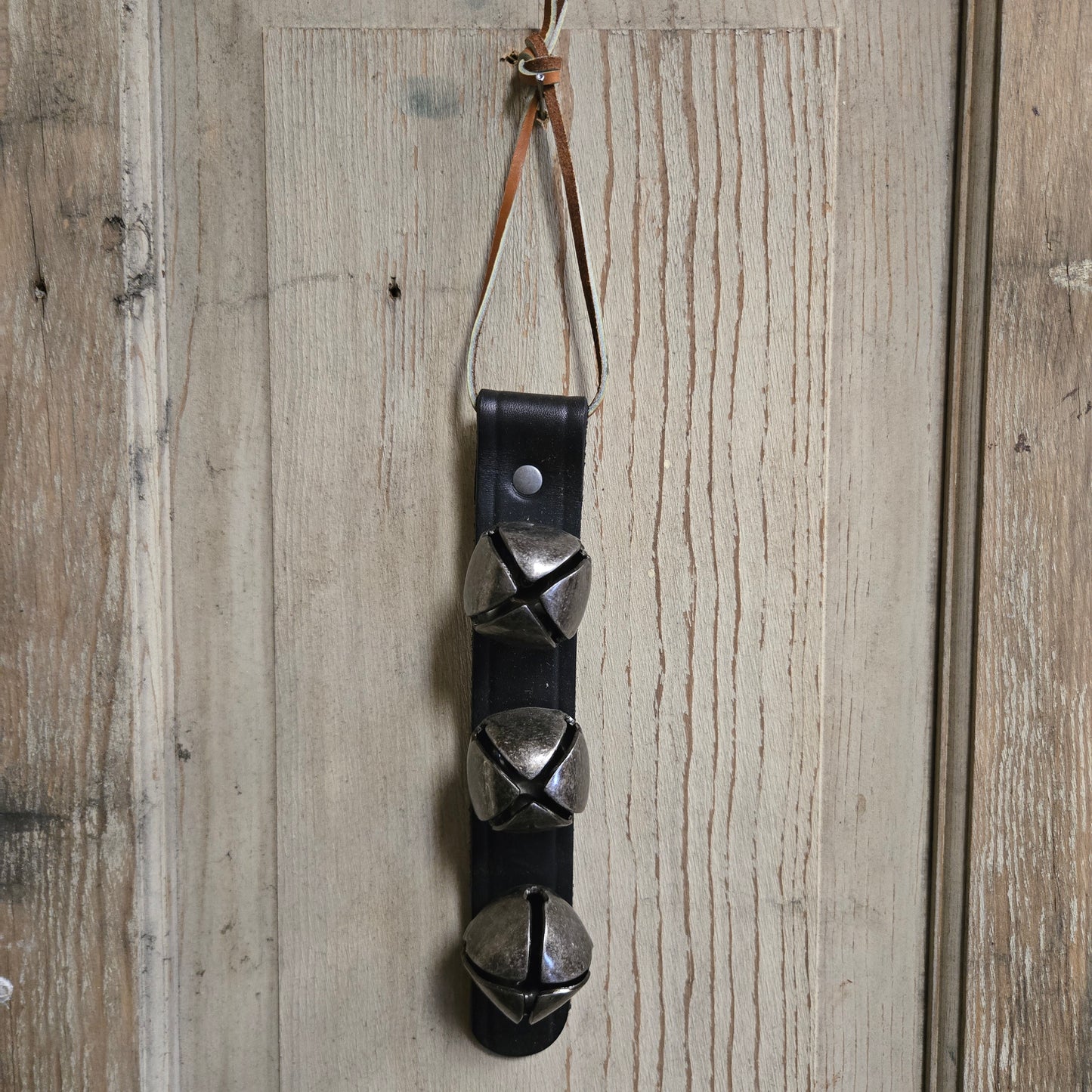 Leather strap with metal bells on a wooden surface