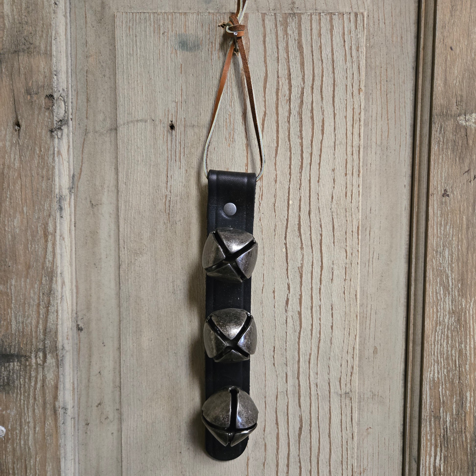 Leather strap with metal bells on a wooden surface