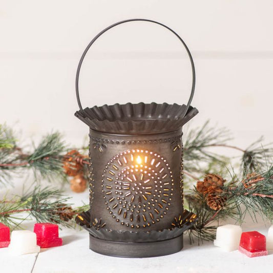 Decorative lantern with a candle inside, surrounded by pine branches and small red and white candles on a light background.