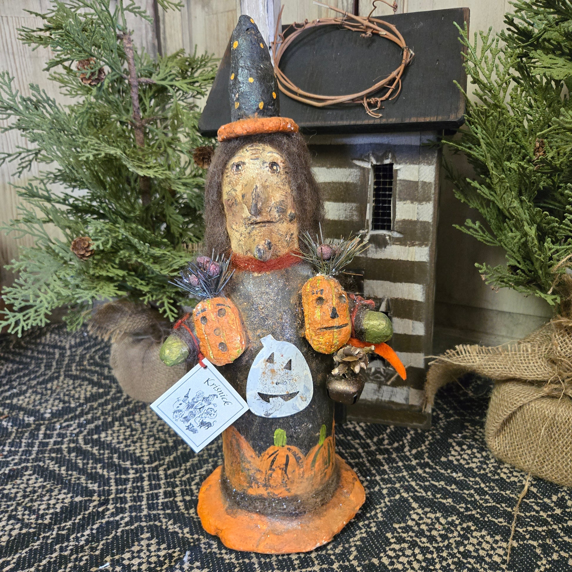 A handcrafted figurine of a witch with pumpkins, intended as Halloween decor.