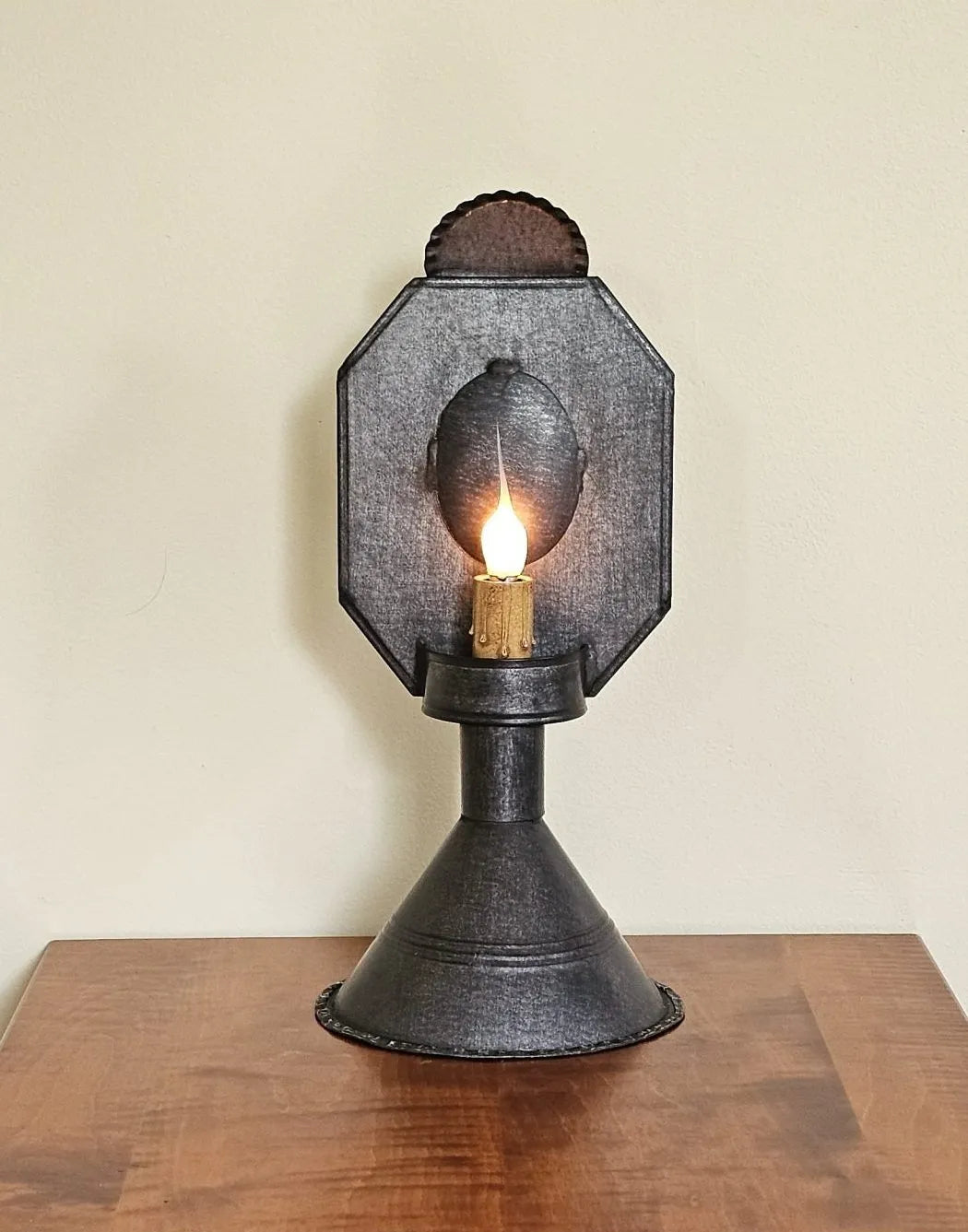 Vintage-style wall sconce with a light bulb on a wooden surface against a beige wall.