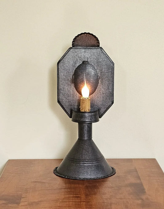 Vintage-style wall sconce with a light bulb on a wooden surface against a beige wall.