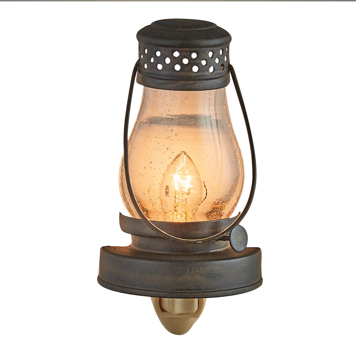 A metal lantern-style night light with a glass diffuser and a lit candle inside, providing a warm glow.