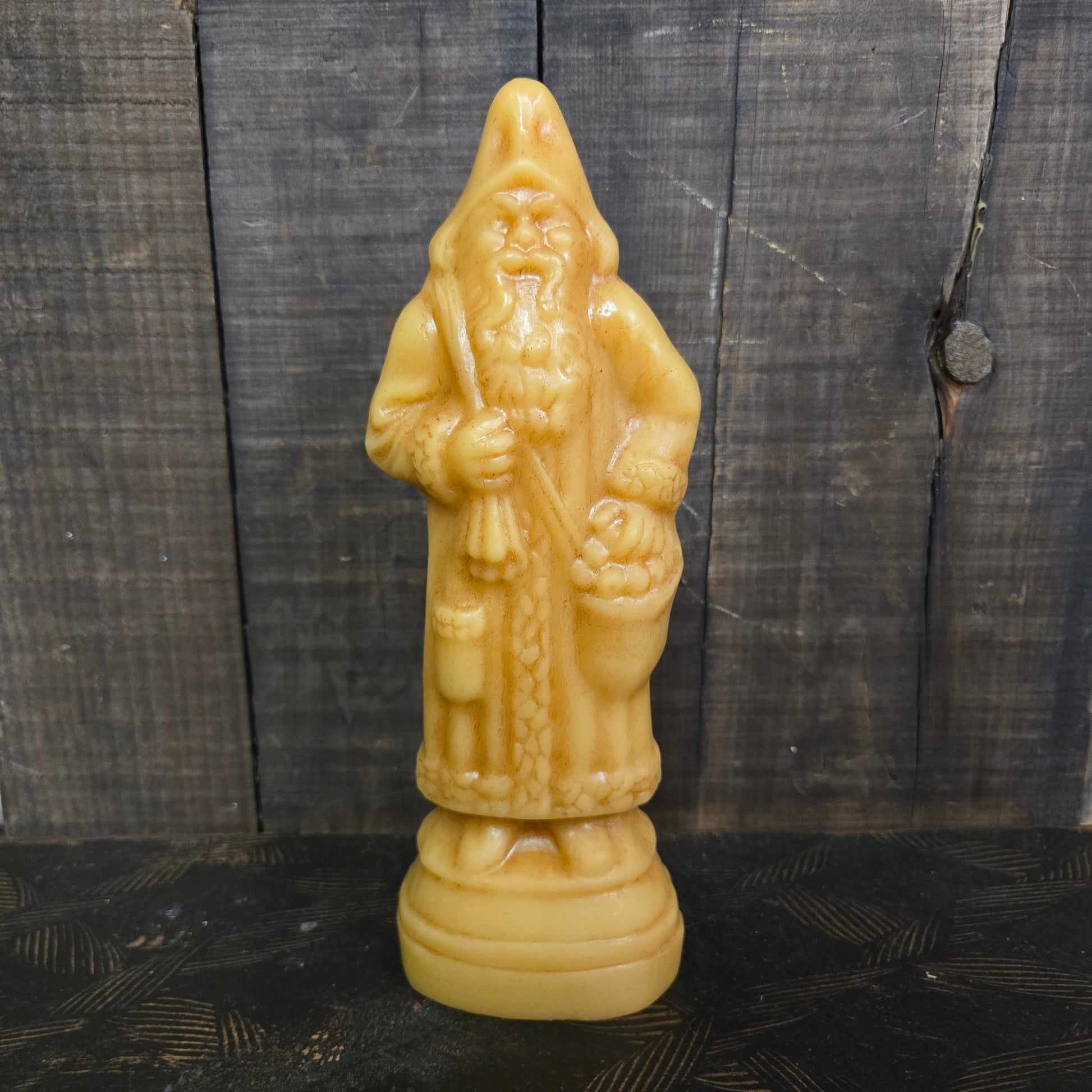 Yellow beeswax Belsnickel figurine on a dark wooden surface