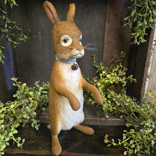 Plush rabbit toy lying on a wooden surface with greenery